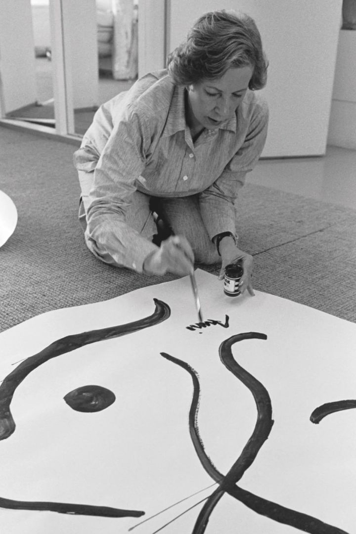 Armi Ratia, de oprichter van Marimekko, tekent haar naam onderaan een schilderij.