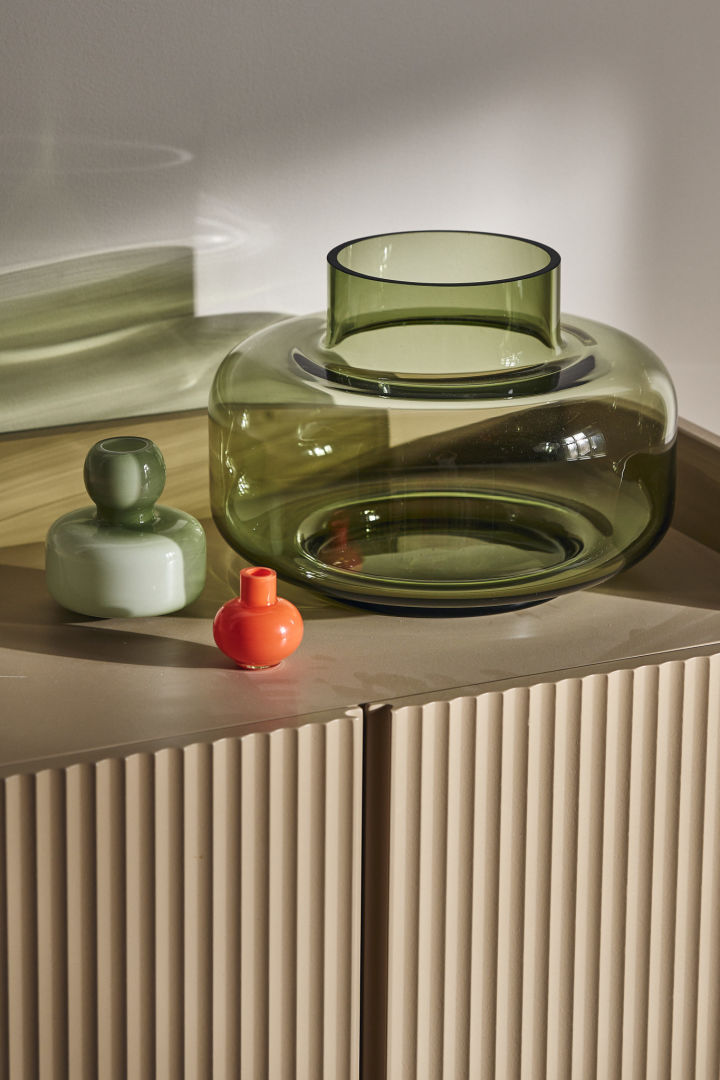 De Urna vaas in groen van Marimekko staat op een kast met de mini vaas in oranje.
